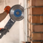 Industrial builder works with professional angle grinder cut bricks build interior walls electrician 150x150